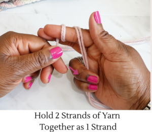 Holding to strands of yarn together to make one strand